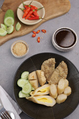 Pempek Palembang, an Indonesian traditional cuisine made from fish cake served with sweet spicy sour sauce and diced cucumber. Piled on white plate on the table