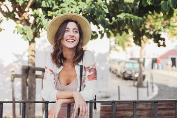 Pretty young woman in a straw hat smiling, walking on the streets of Lisbon, Portugal 