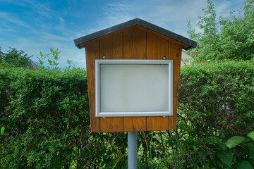 Infotafel vor einer Hecke