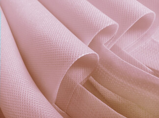 pink polypropylene bag. non-woven fabric with wavy pleats. pile of environmentally friendly bag materials. spunbond bag