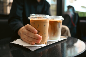 Close up with male's hands holding an iced coffee.