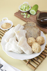 Pempek Palembang, an Indonesian traditional cuisine made from fish cake served with sweet spicy sour sauce and diced cucumber. Piled on white plate on the table