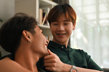 Young millennials Asian male looks at boyfriend's face and touches on his chin, Recognizing gender equality, supporting LGBT people.