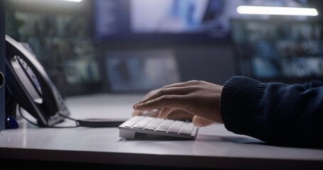 Close up shot of male security operator typing on keyboard. African American man works in police...