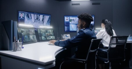 Multi ethnic security operators control CCTV cameras with AI facial scanning in police surveillance...