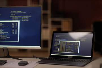 Close-up of computers with security codes on monitors on workplace of programmer