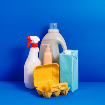 Generative AI illustration of plastic bottles placed near carton egg container on blue background representing concept of recycling packaging
