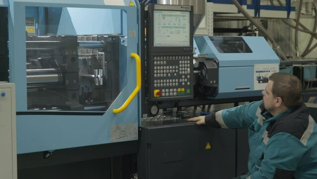 Worker operating the industrial factory machine. Industrial factory machine operator supervises the material production process. Worker monitoring the industrial factory machine on the conveyor line.