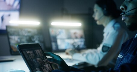 Security officers in headsets control CCTV cameras. Woman uses computer, African American man uses digital tablet with security cameras view. Tracking and monitoring system. Concept of social safety.