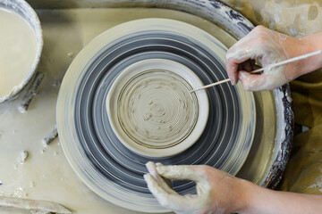Fototapeta premium close up view of professional potter working on pottery wheel at workshop. High quality photo