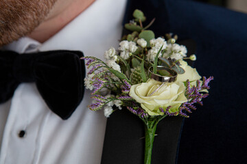 groom with a button hole flower with wedding rings