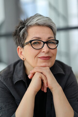 Portrait of a smiling gray-haired woman in glasses.