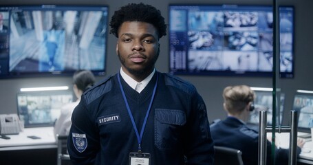 Portrait of African American security officer in police monitoring center looking at camera....