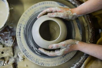 Fototapeta na wymiar close up view of professional potter working on pottery wheel at workshop. High quality photo