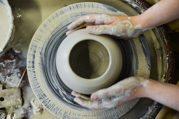 Fototapeta premium close up view of professional potter working on pottery wheel at workshop. High quality photo