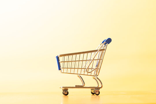 Close up of a shopping cart on a yellow background
