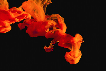 Abstract orange acrylic ink in water.Fluid drop. Paint water.Bright orange color ink smoke cloud floating on abstract dark background.Close-up.Isolated.