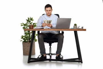 handsome businessman working on laptop and holding money