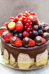 Blue summer cake with fresh berry, cherry, strawberry, raspberry and chocolate sauce on plain grey background