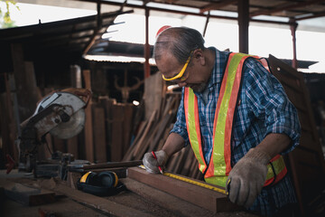 Fototapeta na wymiar An elderly carpenter works the wood with meticulous care.