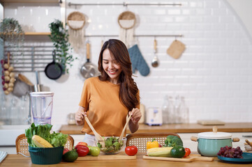 Young Asian woman is preparing a fresh healthy vegan salad with many vegetables in the kitchen, Dieting Concept. Healthy food Lifestyle. Cooking At Home.
