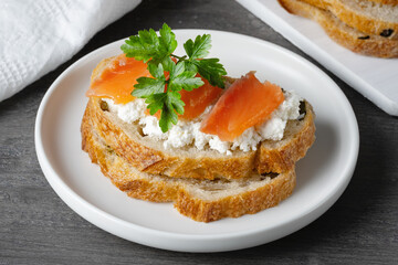 Sandwich with salted salmon and cottage cheese on a gray wooden table