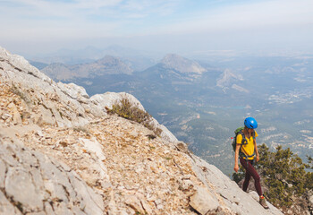 climber with a backpack and a helmet goes along a mountain path in the mountains. Girl climber in the mountains.hiking with a backpack in the mountains.