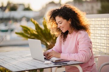 woman sitting in summer cafe working on laptop