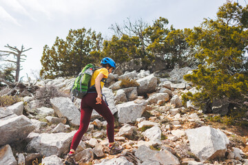 climber with a backpack and a helmet goes along a mountain path in the mountains. Girl climber in the mountains.hiking with a backpack in the mountains.