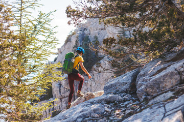 climber with a backpack and a helmet goes along a mountain path in the mountains. Girl climber in the mountains.hiking with a backpack in the mountains.