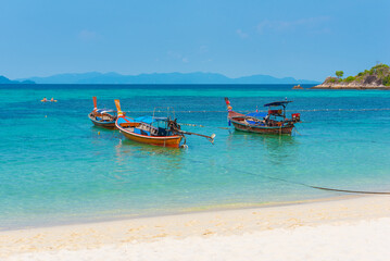 Fototapeta na wymiar Sunrise Beach in Ko Lipe, Thailand. Long-tail boats in azure water.