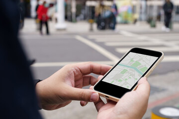 Woman with baggage in downtown city street searching location in map application online on smart phone using GPS navigating.