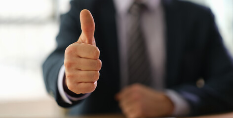 Businessman in suit showing thumbs up on successful deal closeup. Business success concept