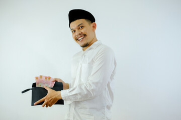 Side view of Moslem Asian man smiling happy when taking money from inside his wallet