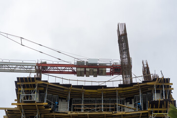Close-up of a construction site, a crane, piles against a gray sky. Construction concept