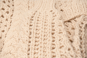 A fragment of beige knitted fabric, knitted from white sheep wool.