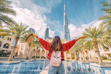 From behind, you can see the traveler girl arms spread wide as she take in the incredible view of the and the Dubai skyline. - obrazy, fototapety, plakaty
