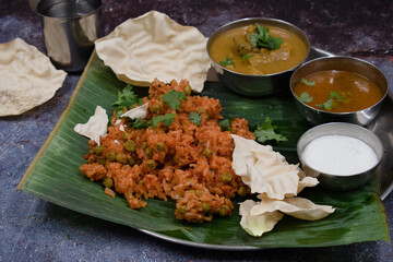 Indian tomato rice served with sambar,  curry, curd on banana leaf
