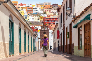 Fototapeta na wymiar Lifestyle, woman on vacation walking through the city of San Sebastian de la Gomera next to the Iglesia De La Asuncion, Canary Islands
