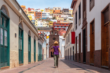 Vacation concept, woman walking through the city of San Sebastian de la Gomera next to the Iglesia De La Asuncion, Canary Islands
