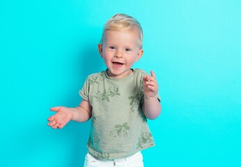Adorable cute Caucasian blond baby boy wearing summer trendy clothes set standing over blue studio background smiling and dancing. 