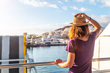 Fototapeta premium A female tourist from the Ferry and the city of Los Cristianos in the background on the island of Tenerife. Ferry coming from La Gomera, Canary Islands