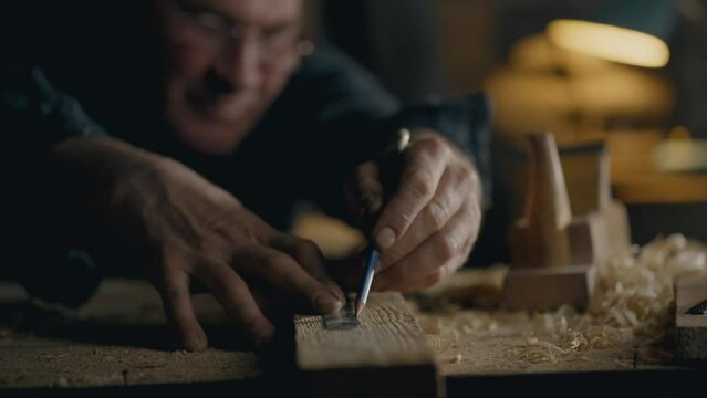 Carpenter, Middle-aged man Absorbed Draws a line with a pencil marking the place of cutting In the workshop Close-up Young expert Works with wood blanks In the workshop, do it yourself
