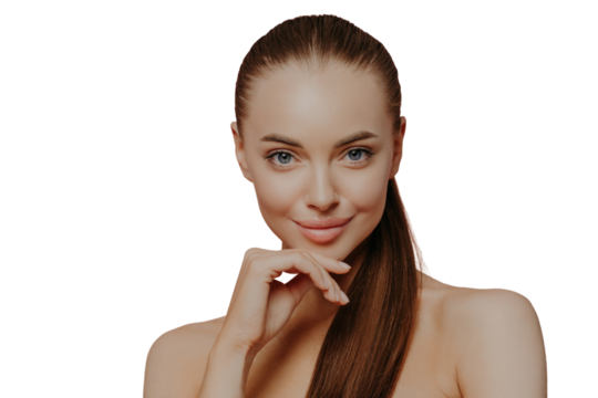 Skin care and anti aging procedures. Confident brunette young woman keeps hand under chin, has combed hair, clean fresh skin, enjoys beauty treatments, poses with naked body over pink background