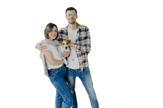 Happy woman and man tenants or renters of flat pose in own house, cuddle and pose with little dog, have glad expressions, start living in new bought apartment. Family and relocation concept.