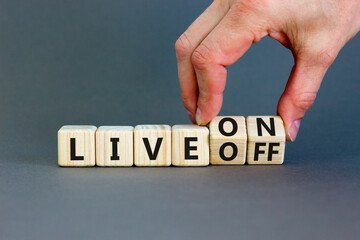 Live on or off symbol. Businessman turns wooden cubes and changes word Live off to Live on....