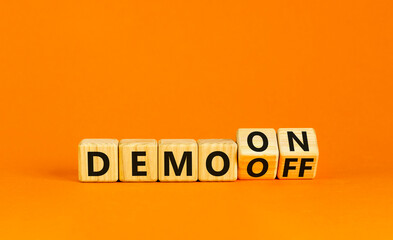 Demo on or off symbol. Businessman turns wooden cubes and changes word Demo off to Demo on. Beautiful orange table orange background. Business and demo on or off concept. Copy space.