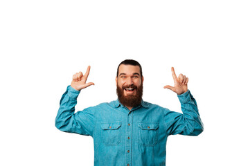 Studio portrait of a hipster bearded excited man pointing up with both his hands.