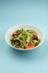 Portion of fresh gourmet salad with salmon on blue background
