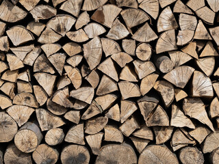 Dry firewood stacked in a pile, chopped wood for winter heating fuel of the fireplace. Natural wood background.